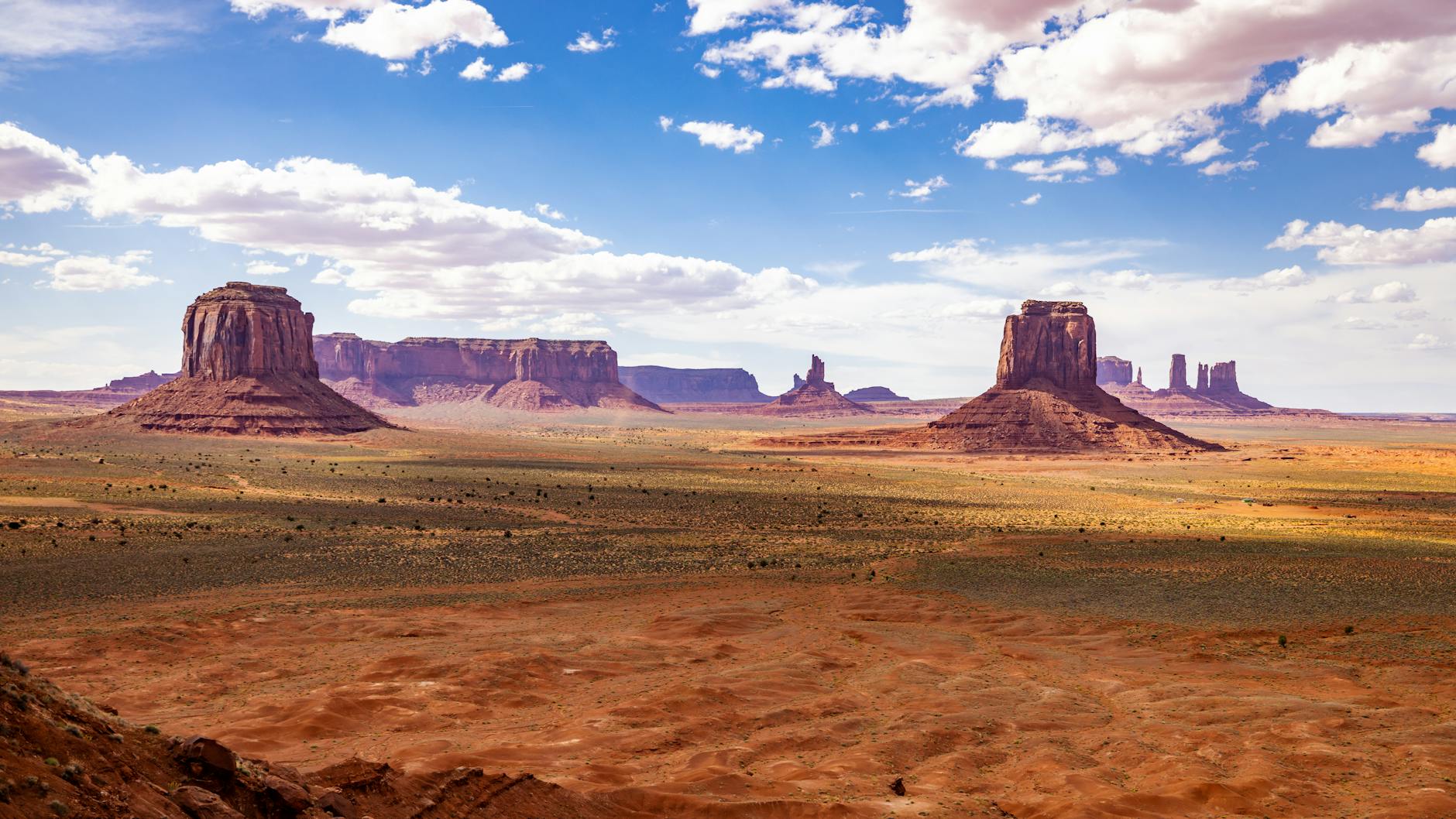 Breathtaking view of rock formations in Monument Valley, Arizona, under a blue sky.